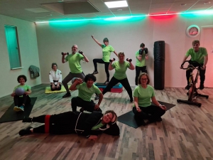 Het team van Sportschool Hierden in een grappige sport pose in hun bedrijfskleding (Fel groene t-shirt en zwarte broek) in totaal 10 personen in de foto